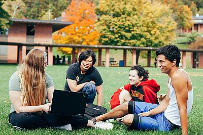  秋天，学生们坐在学生中心外的草地上.