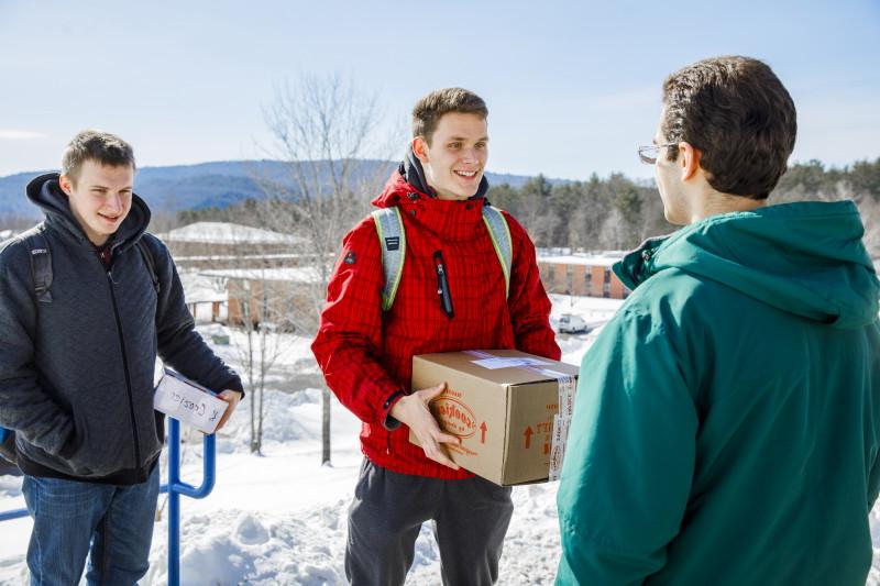 冬天，两名地标学院的学生拿着邮寄的包裹，第三名学生在一旁看着.