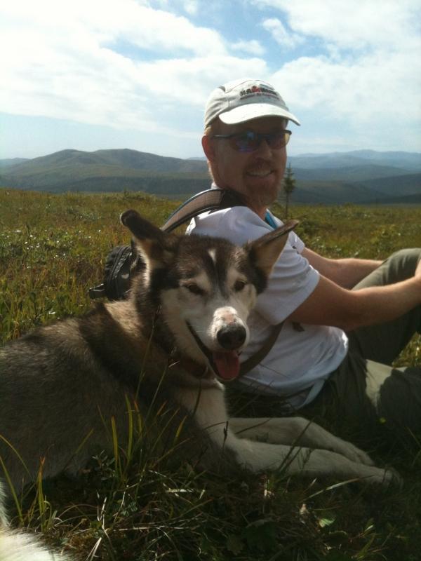 Brian Young with husky dog in foreground and mountains in background